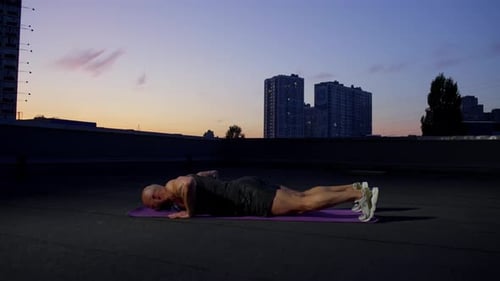 Man Performing Push Ups on Rooftop with Stunning Skyline View
