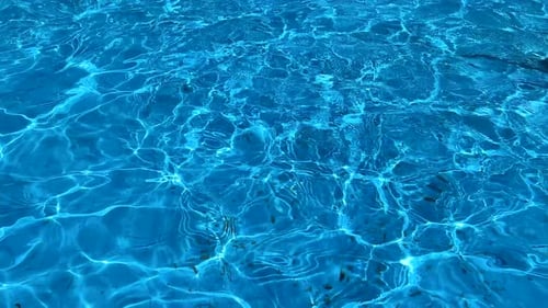 Ondulações de luz na superfície clara da água azul em um dia ensolarado.
