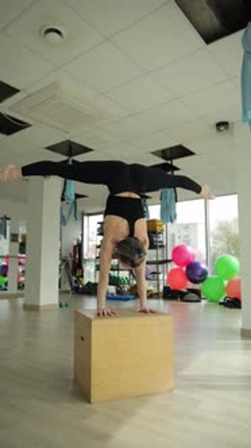 Woman Performing Advanced Yoga Stretch in a Vibrant Gym Vertical Video