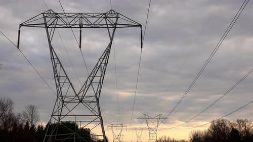 Large electrical pylon in foreground with transmission lines stretching into distance.