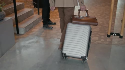Traveler Pulling Suitcase while Entering Hotel Lobby