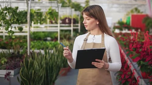 Jolie jeune femme travaillant dans une orangerie à effet de serre