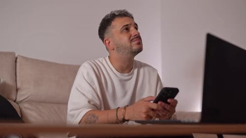 Young Adult Using Phone and Laptop at Home