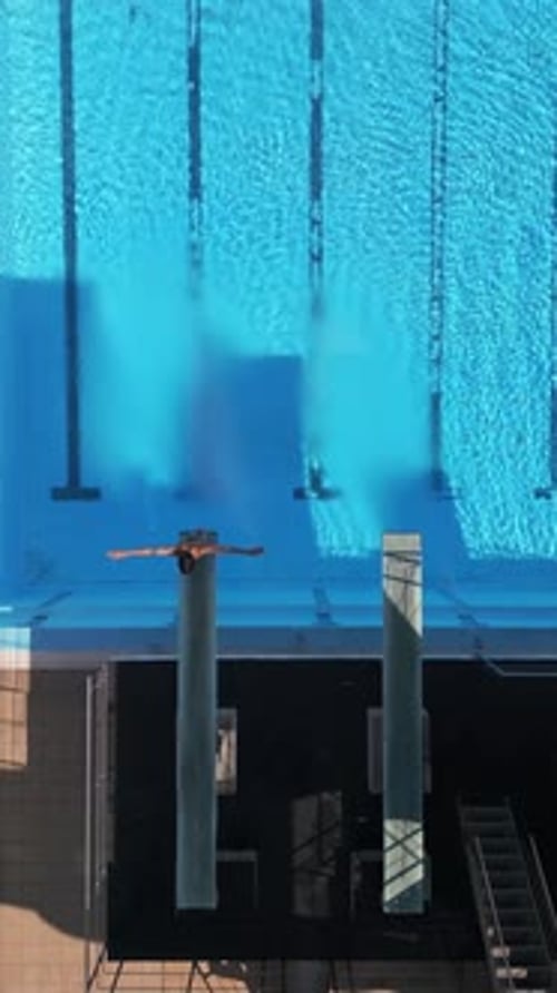 Drohnenaufnahmen, die einen Taucher in der Luft bei einem Tauchgang über einem klaren blauen Pool einfangen, mit atemberaubendem