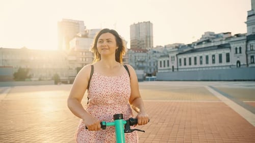 Das Mädchen, das einen sonnigen Tag genießt, fährt mit einem Elektroroller durch die Stadt