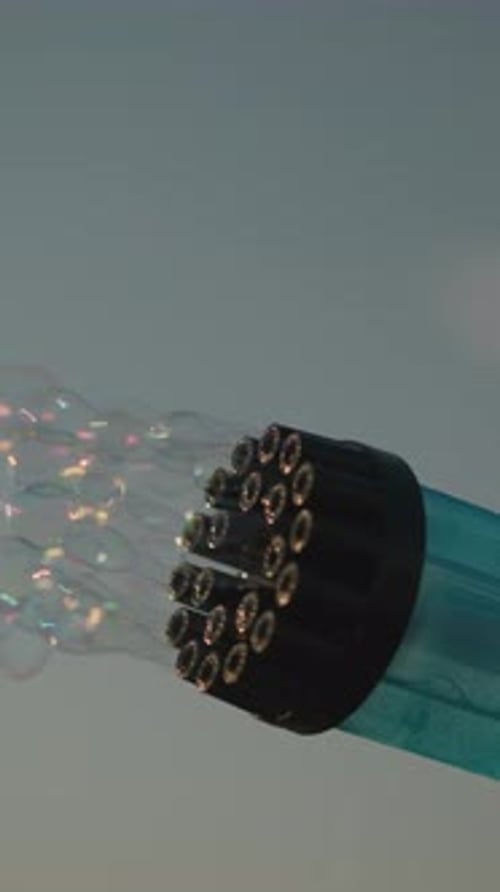 CloseUp of Bubble Gun Releasing Colorful Bubbles Under Clear Sky