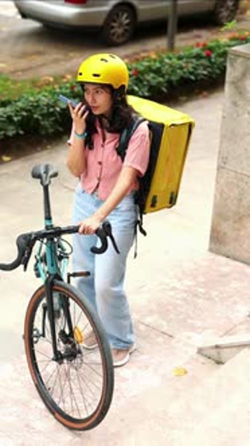 Woman with Bicycle Wearing Helmet and Delivery Backpack