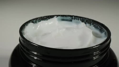 Thick, White Cream in a Black Cosmetic Jar