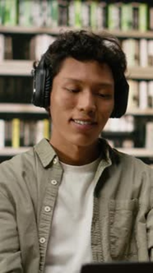 Vertical Video Student with Headphones Reading Open Book and Studying with Focus Music