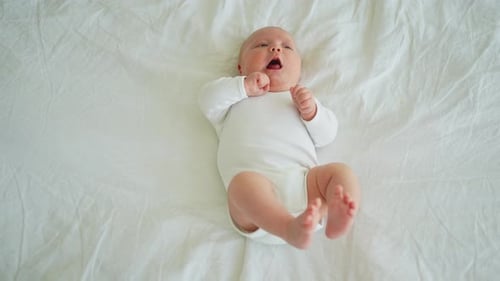 Baby lying on back with white sheet