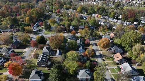 Aerial drone view gliding over a quiet American suburban neighborhood with colorful autumn trees,