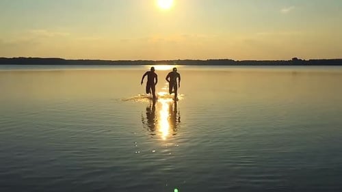 Men Running in Lake Water at Sunset