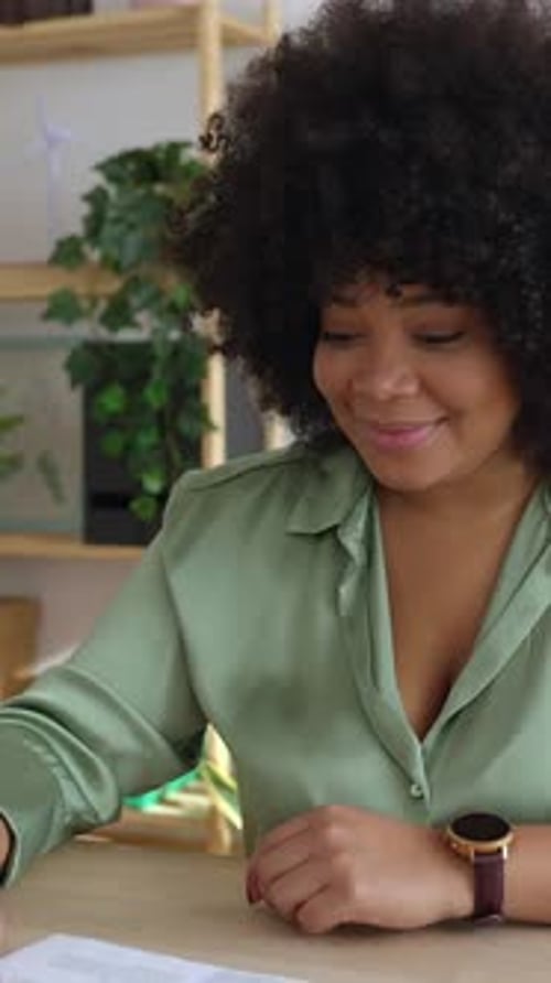 Woman Talking and Reviewing Documents at Desk