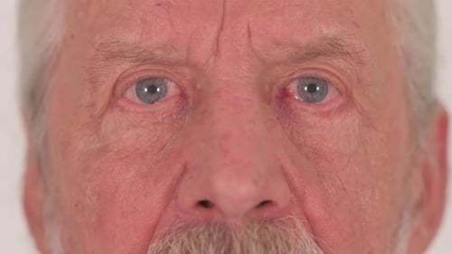 Close up of Senior Male Blinking Eyes on White Background