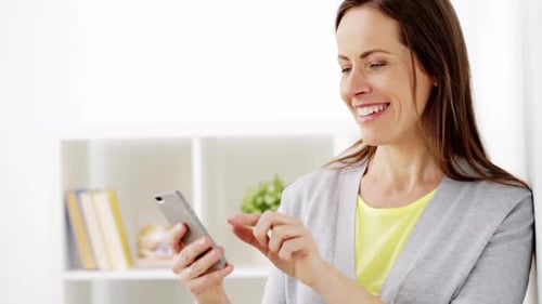 Smiling woman using smartphone in bright room indoors