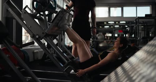 Side View of a Confident Athletic Girl in Summer Sportswear Performing a Leg Press Under the