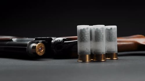 Close-up: loaded shotgun and cartridges on the table, the man takes the cartridge