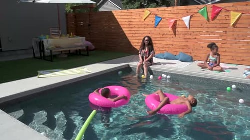 Mutter und Kinder genießen die Sommerferien an einem sonnigen Pool