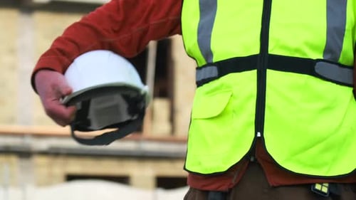 Civil engineer male construction worker holding safety white helmet, close-up, slow motion
