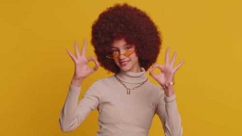 Young Funny School Girl in Glasses Looking Approvingly at Camera Showing Okey Gesture Like Sign