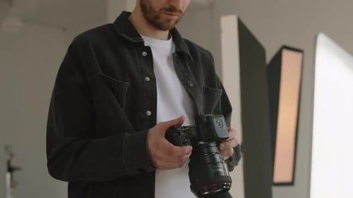 Male Photographer Looking at Photos on Camera Display in Studio