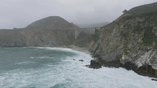 Vorwärts fliegen entlang der zerklüfteten Rocky Coast Concrete Arch Road Bridge über das Tal an der Küste von Kalifornien