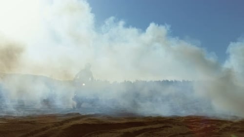 Professional Motocross FMX Motorcycle Rider Drives Through Smoke and Mist Over the Dirt Road Track.