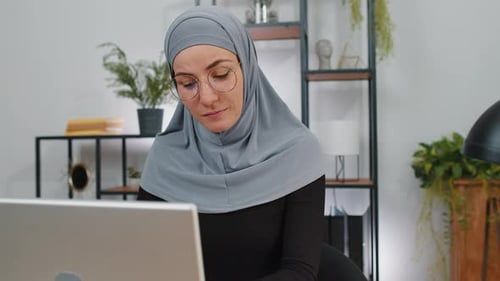 Muslim Business Woman in Hijab Looking at Camera After Finishing Laptop Computer Work at Home Office