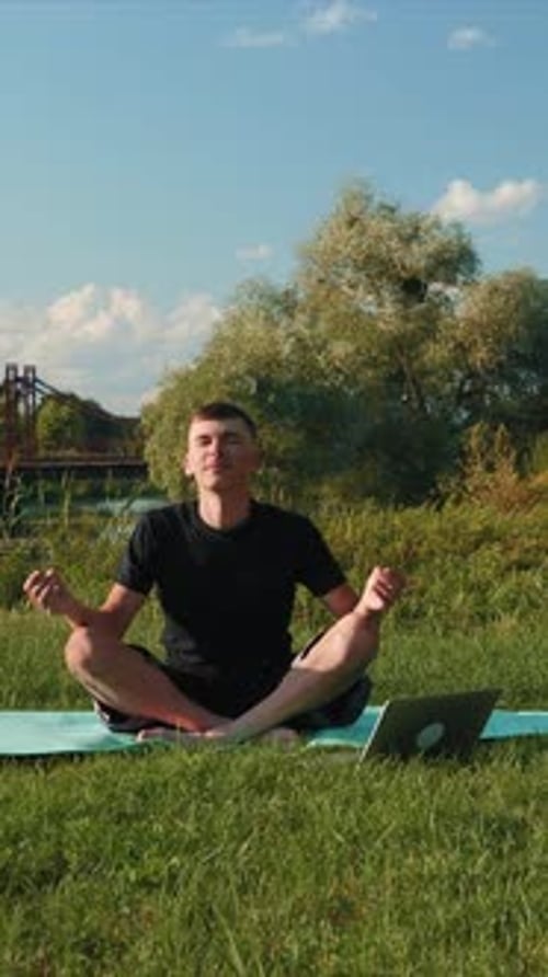 Man Meditating Outdoors with Laptop in Nature