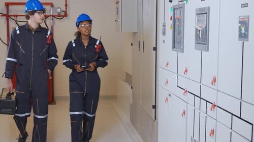 Engineers Inspecting Electrical Control Panels in Substation