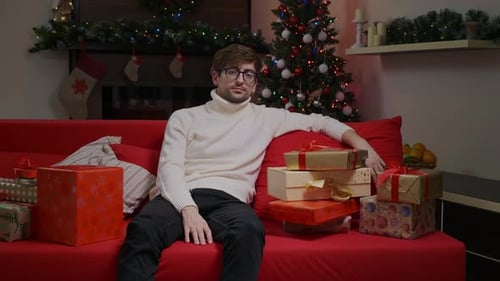 Man on Couch with Christmas Gifts at Home