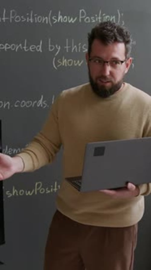 Vertical of Male STEM Teacher with Laptop Explaining Algorithm on Screen