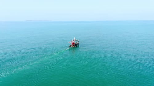 Drone view of small boat in the middle of beautiful calm blue sea