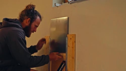 A Man is Adjusting a Sliding Metal Cover on a Small Wall Opening - Close Up