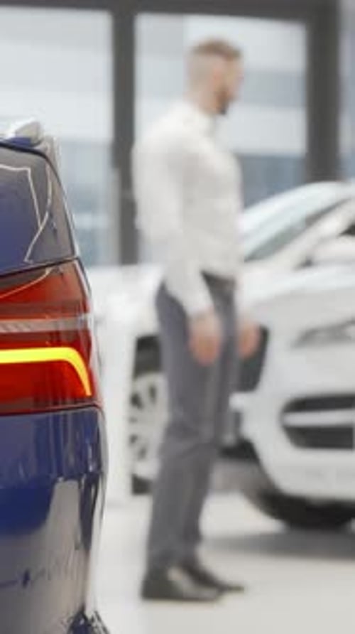 Businessman Thoughtfully Examining Cars for Sale at a Sleek Car Dealership