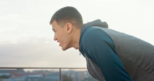 Tired, fitness and man on a break after running, doing workout or exercise in the city of Indonesia