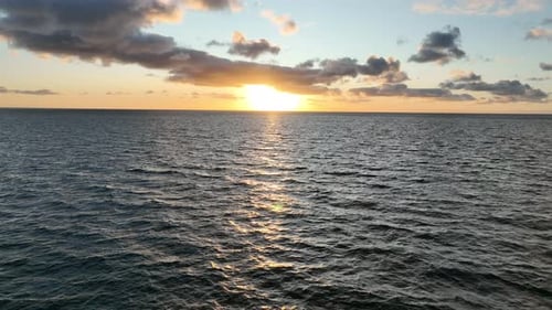Flying low over ocean at sunrise. Camera files backwards looking at sun rising over the ocean. Shot