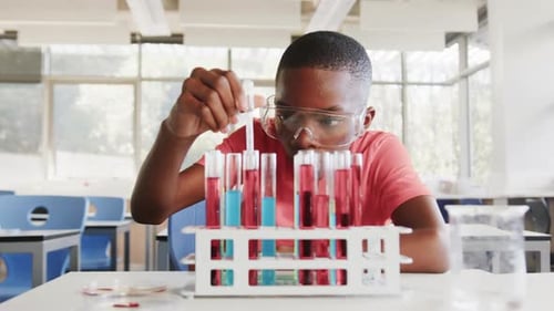 In school, boy conducting science experiment with test tubes in classroom laboratory