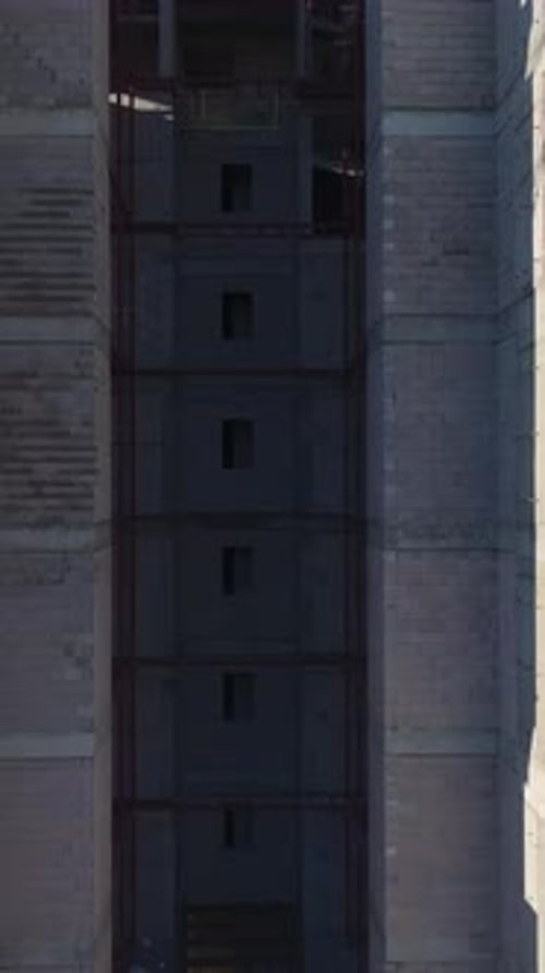 Vídeo vertical de una obra de construcción de viviendas al atardecer con trabajadores vertiendo hormigón y asegurándolo