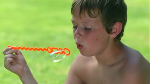 Boy Blowing Bubbles Outside in Sunny Weather