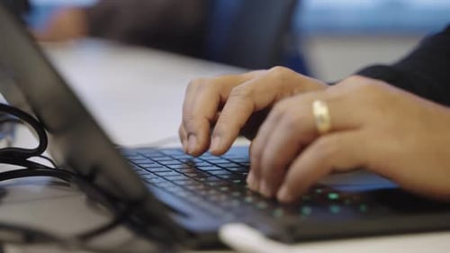 Close up of anonymous married person's hands typing on laptop keyboard in office