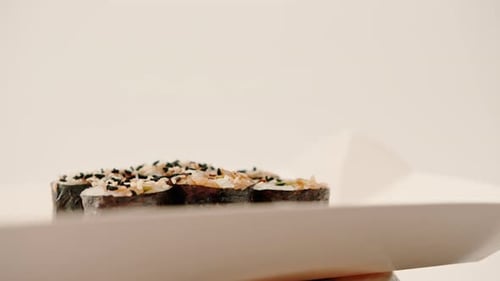 Close-up of maki roll with avocado with soy sauce in sushi delivery box on white background