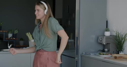 Woman Dancing with Headphones in Modern Kitchen