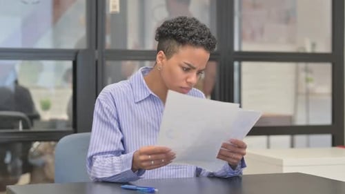 Worried Young Adult Reads Documents in Office