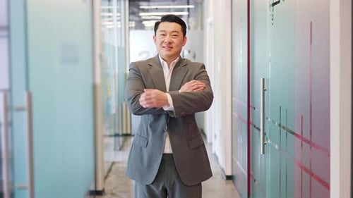 Happy Asian Male Standing in Middle of Modern Office Corporate with Crossed Arms