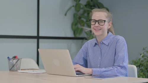 Smiling Woman Working at Laptop in Modern Office