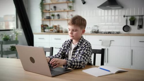 Boy Using Laptop at Kitchen Table