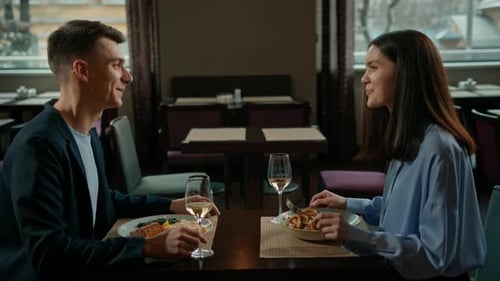 A date in a hotel restaurant a man and a woman drink white wine in glasses the face of smiling girl