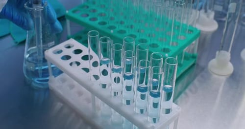 Scientist Pipetting Liquid into Test Tubes in Laboratory