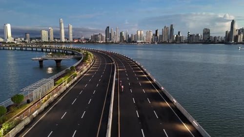 Marathon runners on an luxury avenue by the sea at sunrise with the city in the background.